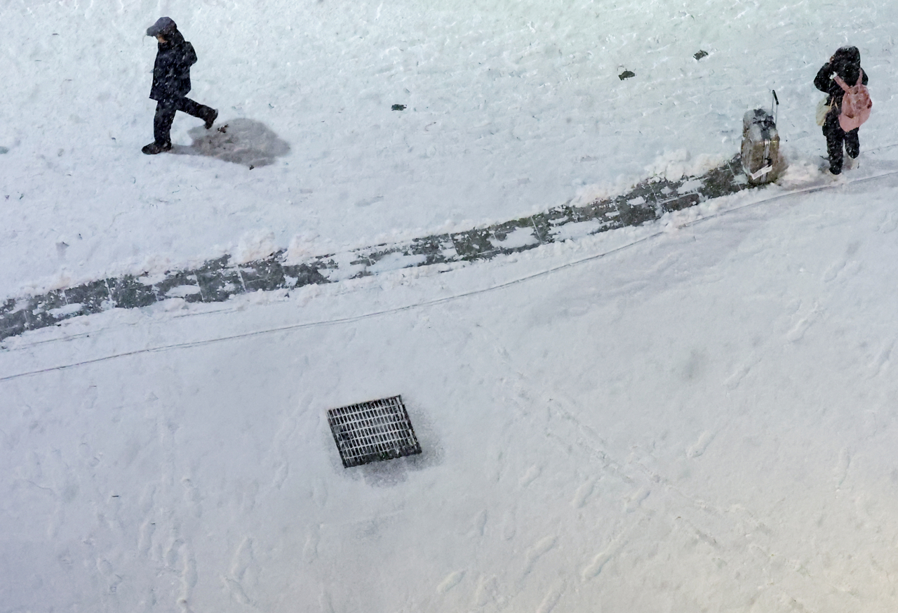 A luggage trail is visible on a Seoul street as the city sees its first snowfall of the season on Thursday. (Yonhap)